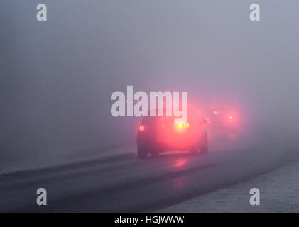 Guida nella nebbia. I fendinebbia delle auto brillano attraverso una fitta nebbia gelida che rende pericolose le condizioni di guida per i conducenti durante la mattinata invernale su strada di campagna. New Forest Hampshire, Regno Unito. Gennaio. Foto Stock