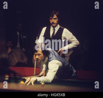 Alex "uragano' Higgins al tavolo come il suo avversario canadese Cliff Thorburn guarda su durante la finale di Embassy World Snooker Championship al Crucible Theatre di Sheffield. Thorburn rivendicato il trofeo e di £ 15.000 Premio battendo Higgins da 18 fotogrammi a 16. Foto Stock