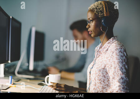 African American donna che indossa gli occhiali lavorando sul desktop in ufficio Foto Stock