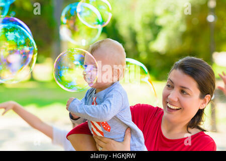 Carino il bambino e sua madre la cattura di bolle di sapone in un giorno di estate Foto Stock