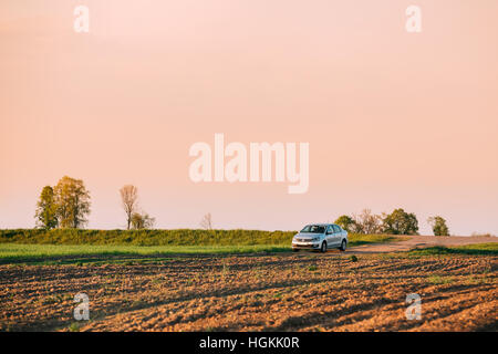 Gomel, Bielorussia - Maggio 04, 2016: Volkswagen Polo berlina auto parcheggio sul campo di grano. Sunset Sunrise colore giallo Sky su uno sfondo nella soleggiata sera. Foto Stock