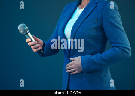 Elegante giornalista femmina la conduzione di affari intervista o conferenza stampa, mano con microfono Foto Stock