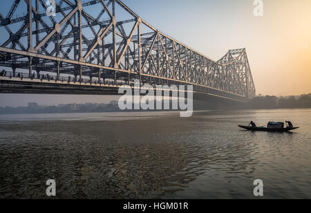 La barca di legno passa il quella di Howrah ponte sul Fiume Hooghly a sunrise. quella di Howrah bridge è i Mondi sesto ponte più lungo del suo genere. Foto Stock