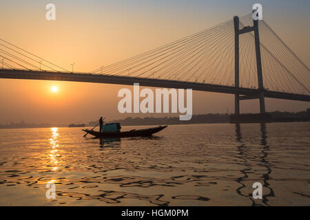 La barca di legno sul Fiume Hooghly al tramonto con Vidyasagar Setu ponte a sfondo. Questo è il più lungo ponte strallato in India. Foto Stock