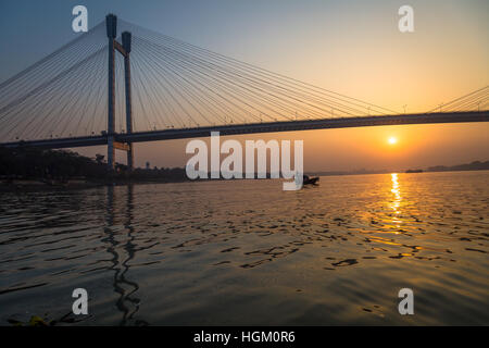 La barca di legno sul Fiume Hooghly al tramonto con Vidyasagar Setu ponte a sfondo. Questo è il più lungo ponte strallato in India. Foto Stock