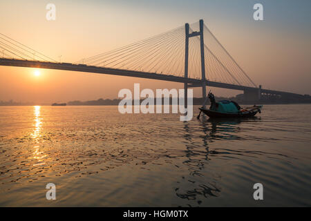 La barca di legno sul Fiume Hooghly al tramonto con Vidyasagar Setu ponte a sfondo. Questo è il più lungo ponte strallato in India. Foto Stock