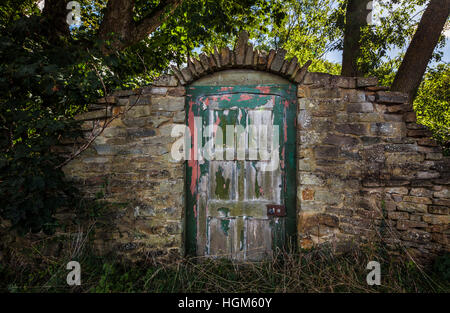 Vecchio giardino porta in un muro di mattoni con sfald vernice Foto Stock