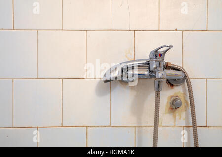 Dettagli di un vecchio, secco e rubinetto inutilizzati su bianco piastrelle del bagno. Foto Stock