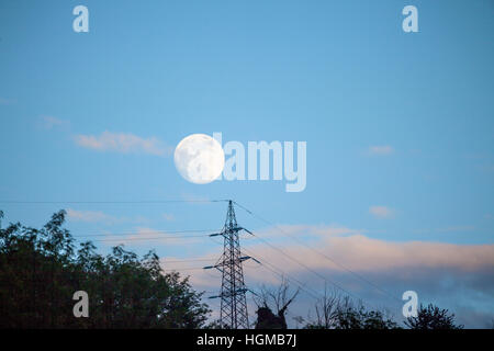 Luna piena sopra i cavi elettrici Foto Stock