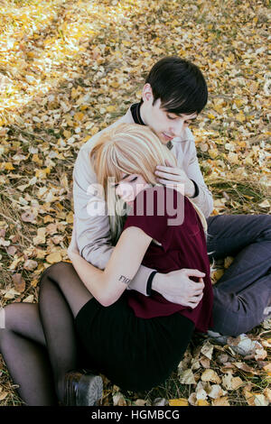 Coppia giovane costeggiata a vicenda in un parco in autunno Foto Stock