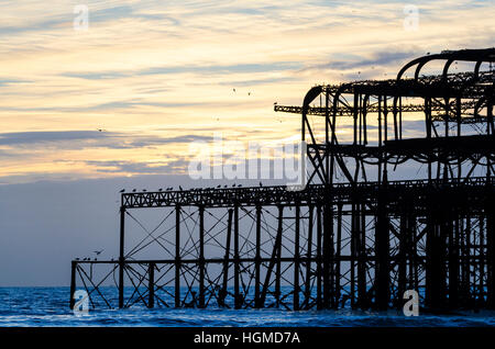 Brighton, East Sussex. Il 10 gennaio 2017. Il sole fa capolino tra le nuvole al tramonto dopo un altro fredda ma piacevole giornata a Brighton, mentre gli storni si scende su dei derelitti Molo Ovest per prendere posatoio per la notte. Temperature sulla costa sud si prevede un ulteriore calo verso il fine settimana. Credito: Francesca Moore/Alamy Live News Foto Stock