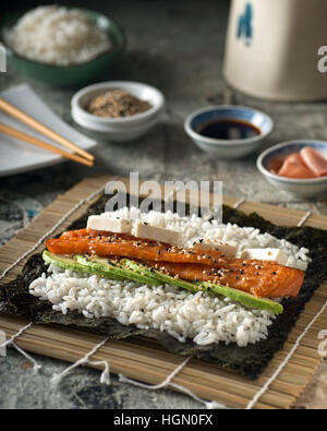 Un delizioso salmone affumicato sushi roll con avocado, crema di formaggio e di semi di sesamo tostati. Foto Stock