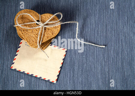 Regalo per il giorno di San Valentino. Gingerbread a forma di cuore, lettera nella busta per una persona amata. Spazio di copia Foto Stock