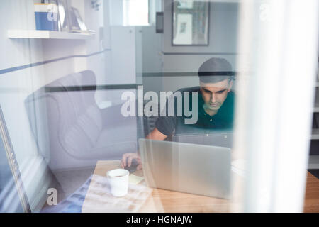 Giovane uomo al lavoro su un portatile a casa Foto Stock
