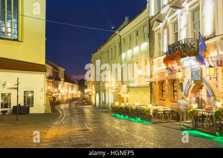 Vilnius, Lituania - 8 Luglio 2016: La Scenic curva deserta Pilies Street della Citta Vecchia di brillante illuminazione serale con antico edificio e Narut Foto Stock