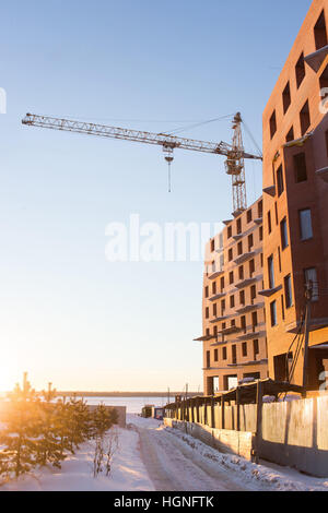 Gru a torre e il nuovo edificio di mattoni rossi è in costruzione. Inverno giornata di sole Foto Stock