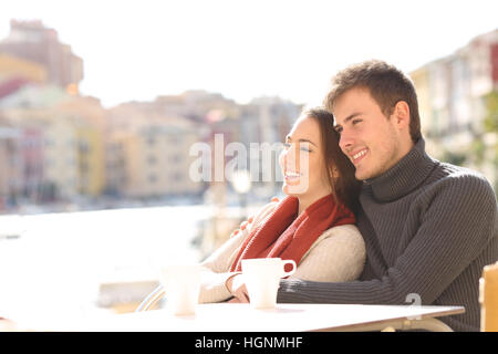 Coppia seduta rilassante in un hotel terrazza su vacanze con una porta in background in una giornata di sole di inverno Foto Stock