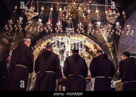 Gerusalemme, Israele - Luglio 18, 2014: monaci francescani pregare dalla crocifissione altare nella chiesa del Santo Sepolcro durante la via dolorosa la precessione. Foto Stock