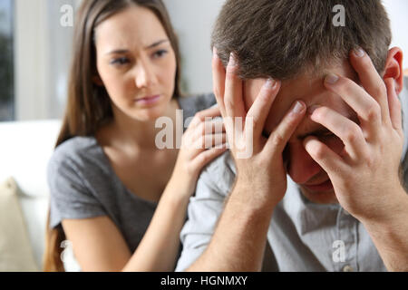 Triste uomo e un amico o amica cercando di consolarlo a casa. Il concetto di amicizia Foto Stock