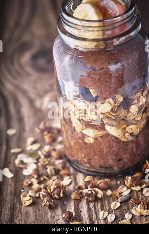 Cioccolato budino di Chia con fiocchi di avena in un barattolo di vetro sul tavolo di legno Foto Stock