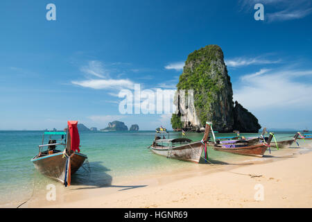 Colorata lunga coda barche alla bellissima spiaggia Ao Nang su uno sfondo di cielo blu e azzurro mare e rocce calcaree, le Isole Phi Phi, Thailandia Foto Stock