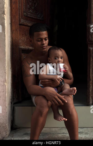 Vero popolo cubano: Ritratto di un giovane nero dell'Avana, Cuba. Padre e figlio ispanici che guardano la telecamera. Padre orgoglioso che tiene un figlio maschio Foto Stock