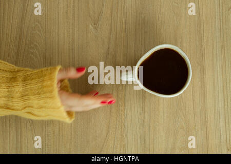 Donna con mano manicure rosso sta per prendere una tazza di caffè Foto Stock