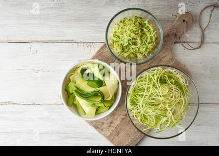 Raw tagliatelle di zucchine sul bianco tavolo in legno vista superiore Foto Stock