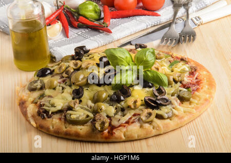 Pane appena sfornato la pizza con olio d'oliva, il basilico e il formaggio fuso su una tavola di legno Foto Stock