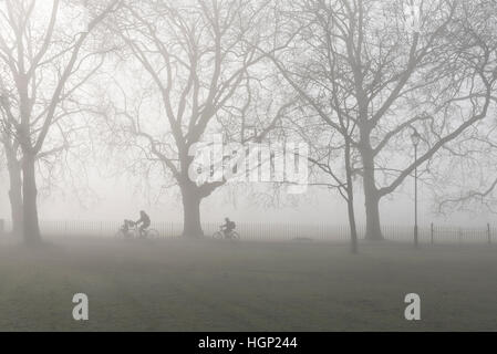 Un genitore e 2 bambini escursioni in bicicletta a scuola nella nebbia mattutina. Foto Stock