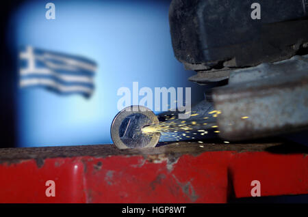 Un Euro monete in una morsa essendo tagliato con una smerigliatrice angolare mentre bandiera greca vola in background Foto Stock