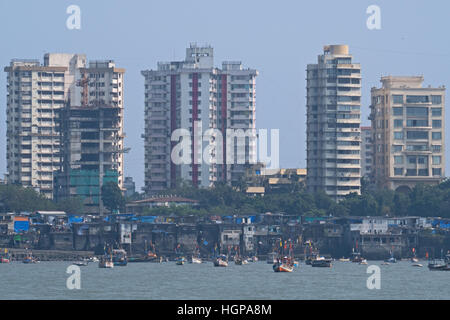 Barche da pesca ormeggiate nella parte anteriore del carter tradizionale nel quartiere di Colaba a Mumbai, con moderni blocchi a torre dietro di loro Foto Stock