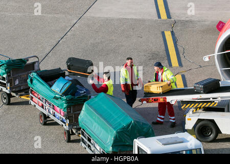 I gestori dei bagagli lo scarico dei bagagli da un aeroplano a Dusseldorf Airport. Foto Stock