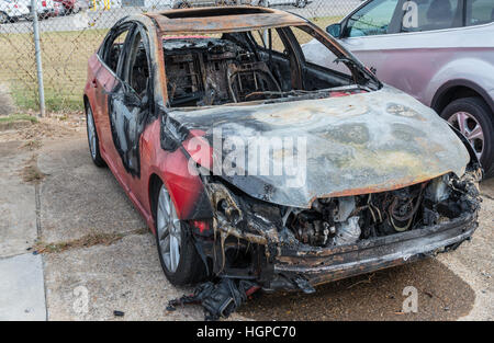 I resti di un auto bruciata a sedersi in un cantiere di demolizione dopo che è stato consumato da un incendio. Foto Stock