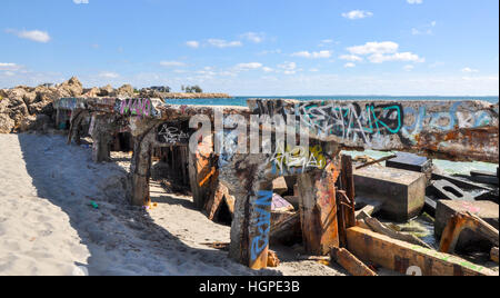 Diga in calcestruzzo con il tagging della gioventù e blocchi di cemento in sabbia sulla costa dell'Oceano Indiano in Nord Coogee,Western Australia. Foto Stock