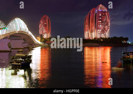 Phoenix Island Resort e complesso di appartamenti illuminata di notte nel porto di Sanya Foto Stock