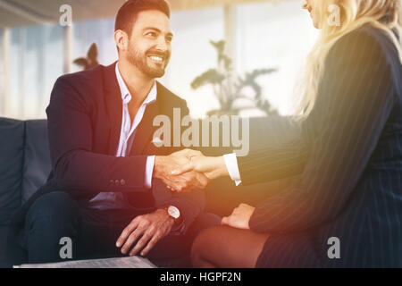 Imprenditore handshake con imprenditrice nel tramonto in ufficio Foto Stock