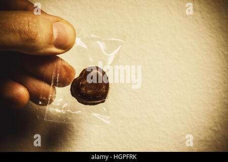 Cuore di cioccolato avvolto in una busta di plastica in mano maschio, composizione concettuale circa dare amore. Foto Stock