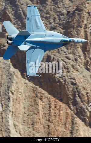 Marina degli Stati Uniti Super Hornet, F-18E, bancario attraverso un canyon del deserto, la formazione di condensa sulle ali di un tira G. Foto Stock