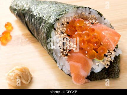 Vista ravvicinata della cucina giapponese sushi roll con salmone e caviale servito di sesamo sulla tavola di legno Foto Stock