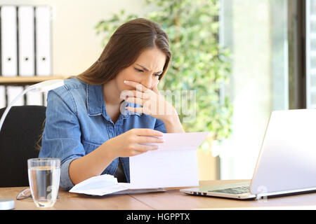 Preoccupati di imprenditore ragazza che lavora in ufficio la lettura di cattive notizie in una lettera su un computer desktop Foto Stock