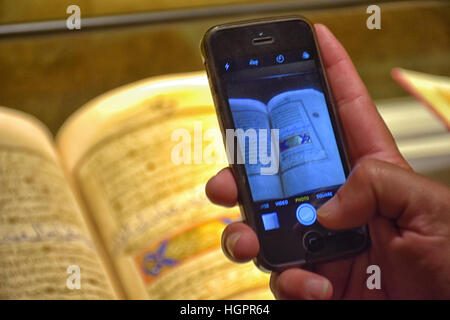 Un uomo scatta una foto con il suo telefono cellulare di rari manoscritti del Corano su visualizzato presso il Santo Corano Exhibition, Medina, Arabia Saudita Foto Stock