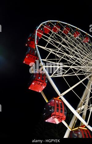 Verso l'alto prospettica di un rosso e bianco ruota panoramica Ferris illuminato contro un nero cielo di sera in Fremantle, Western Australia. Foto Stock