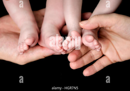 Little Baby gemelli piedi nelle mani dei genitori. Paternità e maternità, famiglia, gemelli, i bambini e il concetto di amore. Foto Stock