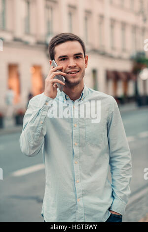 Bel giovane uomo parlando al cellulare nella città Foto Stock