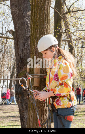 La ragazza si arrampica ostacoli del parco di corda in chiaro giorno di estate Foto Stock