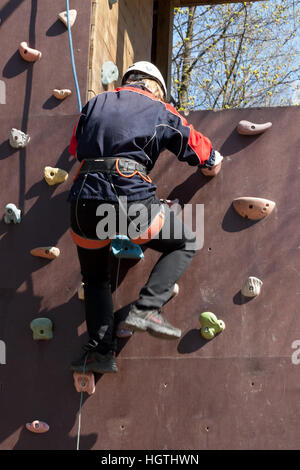 La ragazza si arrampica ostacoli del parco di corda in chiaro giorno di estate Foto Stock