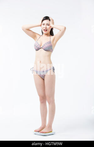 Stressante giovane donna in bikini in piedi su una scala Foto Stock