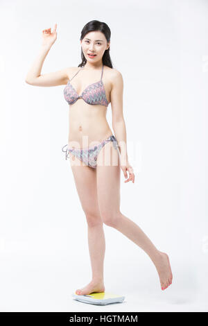 Giovane donna in bikini intensificazione su una scala Foto Stock