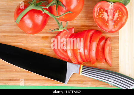 Intero e fette di pomodoro su di un tagliere Foto Stock